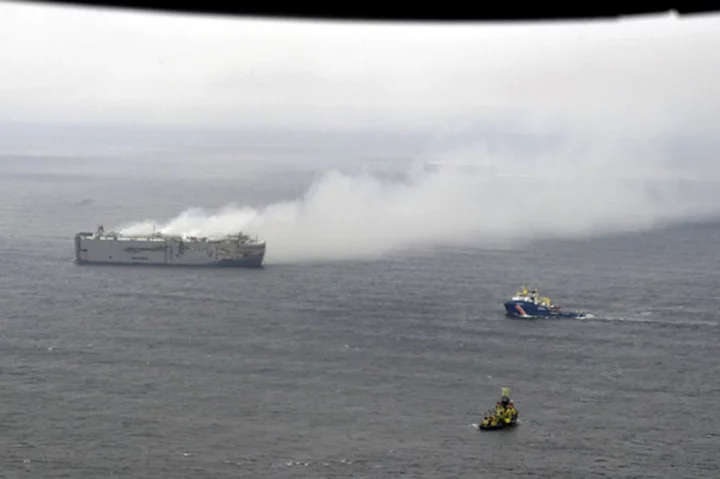 Salvage crews board a cargo ship burning off the Netherlands. The smoke and flames are easing